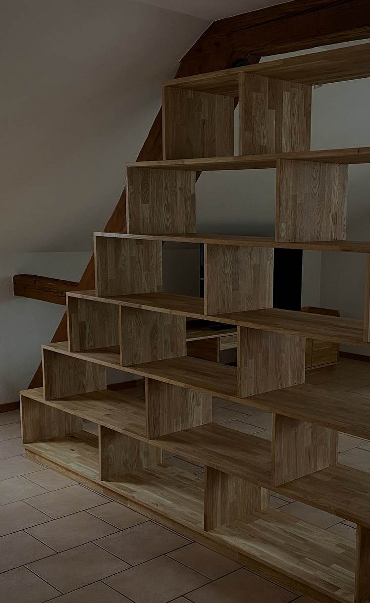 Bibliothèque en escalier en bois massif, réalisée sur mesure sous les combles